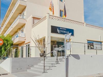 Lichtgekleurd meerlaagse hotel met trappen en balkons, onder een zonnige hemel.