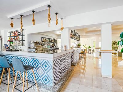 Moderne hotelbar met blauw patroon aan de balie en blauwe barkrukken.