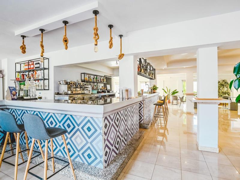 Moderne hotelbar met blauw patroon aan de balie en blauwe barkrukken.