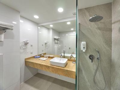 Moderner Badebereich mit eckigem Waschbecken, hölzerner Ablage und Glasdusche mit Regenduschkopf.