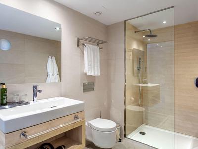 Helles Badezimmer mit Doppelwaschbecken, Toilette und geräumiger Dusche mit Glaswand.