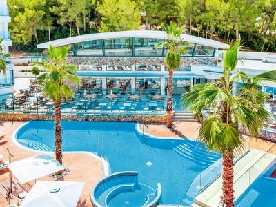 Großer blauer Pool mit Palmen und Sonnenliegen in einem hellen, modernen Hotelgartenbereich.