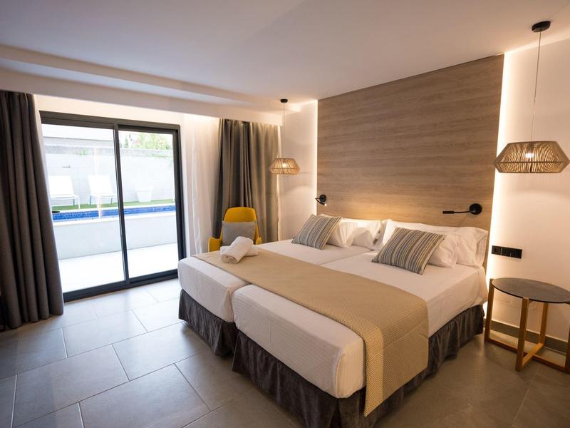 Habitación de hotel moderna con cama doble, balcón y zona de estar.