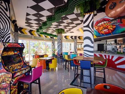 Buntes, modernes Frühstücksrestaurant mit Arcade-Spielen und geometrischem Wanddesign in einem Hotel.