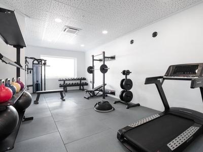 Moderner Fitnessraum mit Laufband, Gewichten und Trainingsgeräten in Hotelumgebung.