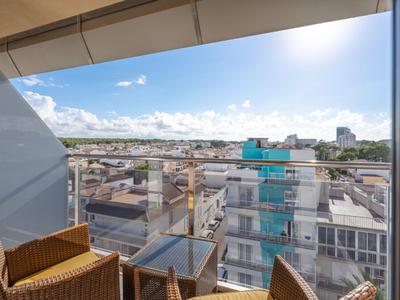 Moderner Balkon mit Stühlen und Glasgeländer mit Blick auf die Stadt und den Himmel.