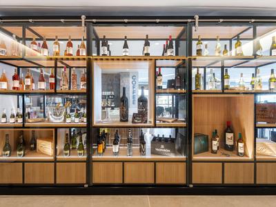 Moderner Holz- und Metalldisplay mit Weinflaschen in einer Hotellounge.
