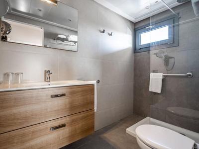 Modernes Badezimmer mit Holzmöbeln und großer Spiegel, Fenster obendrauf.