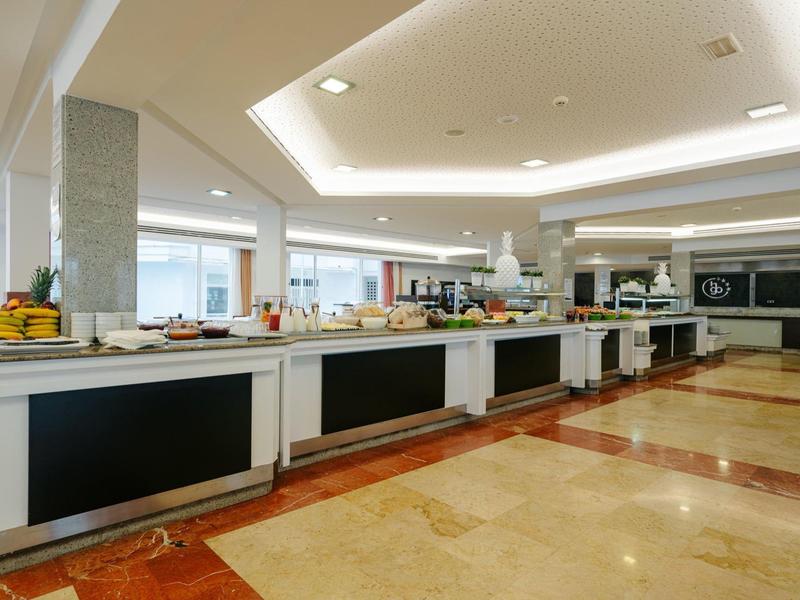 Ruime, moderne buffetruimte in een hotel met witte toonbanken en natuurlijk licht.