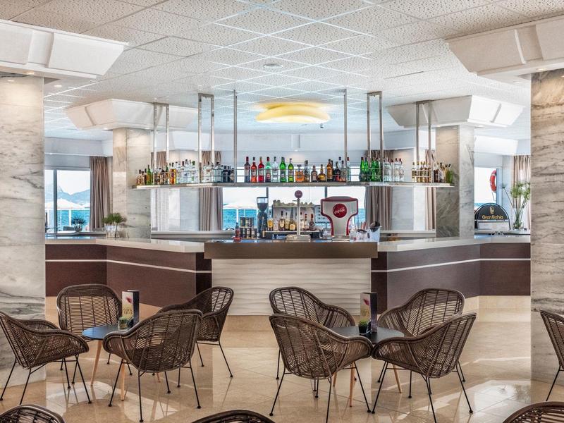 Moderne hotelbar met rotan stoelen, elegante verlichting en panoramisch uitzicht op de oceaan.