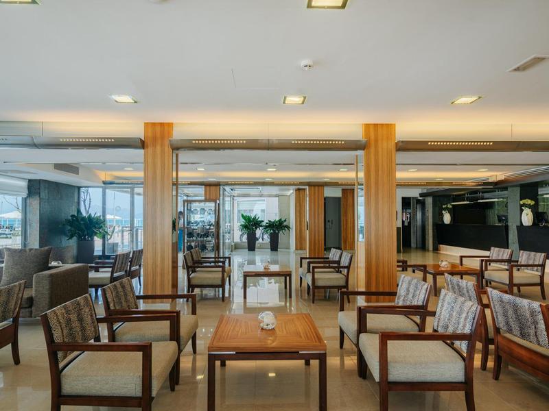 Ruime hotel lobby met gerangschikte zitplaatsen, houten tafels en gepolijste marmeren vloeren.