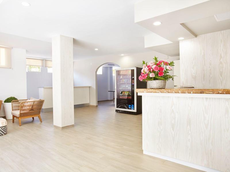 Espace lounge d'hôtel lumineux avec meubles blancs, vitrine et sièges