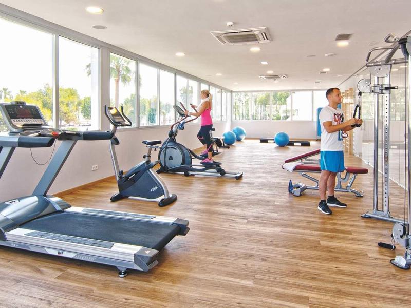 Jasna siłownia z nowoczesnym sprzętem i widokiem na zewnątrz.