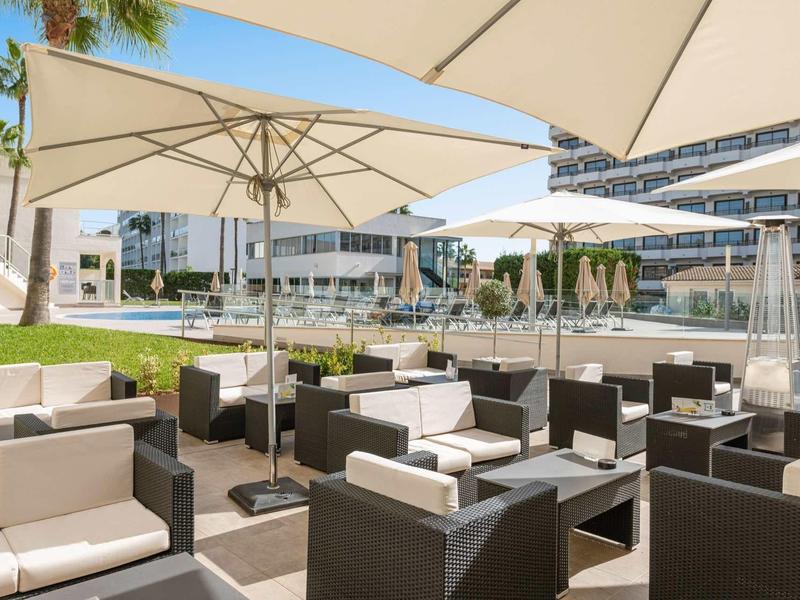 Taras hotelowy z wygodnymi fotelami i parasolami, nowoczesna atmosfera relaksu.