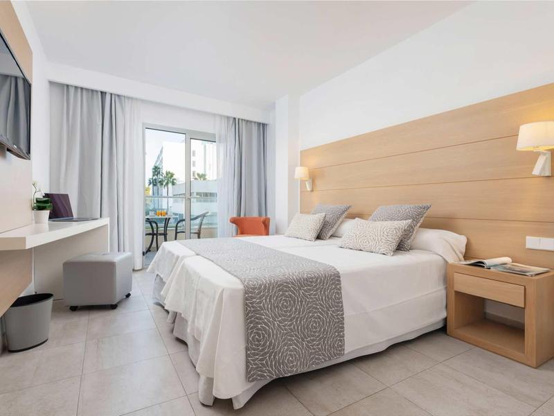 Nowoczesny pokój hotelowy z łóżkiem podwójnym, balkonem i prostą dekoracją.