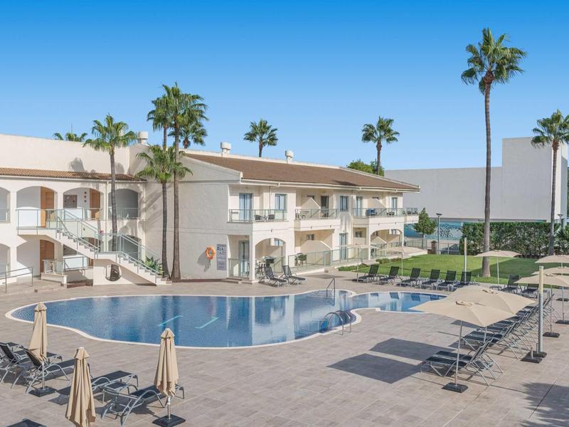 Basen na zewnątrz z leżakami i palmami w ośrodku hotelowym.