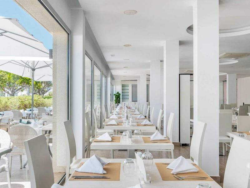 Jasna jadalnia z elegancko nakrytymi stołami i widokiem na zewnętrzny taras.