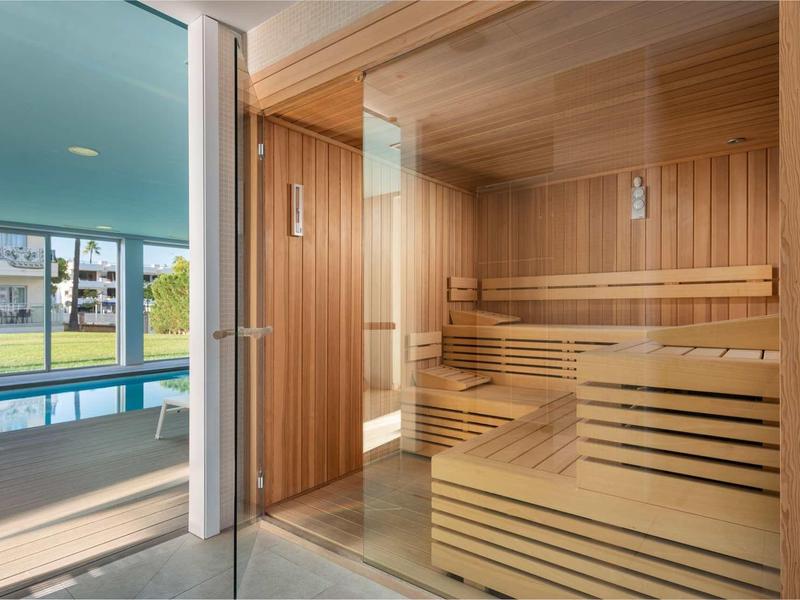 Drewniana sauna z widokiem na zewnętrzny basen i ogród.