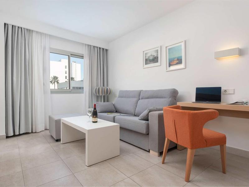 Nowoczesny salon z szarą sofą, białym stolikiem i pomarańczowym krzesłem przy biurku.