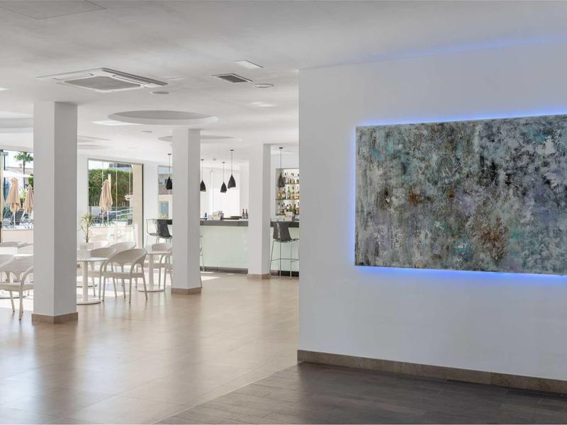 Nowoczesny hol hotelowy z podświetlonym obrazem i eleganckimi białymi krzesłami.