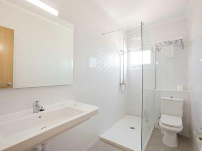 Salle de bain lumineuse avec grand lavabo, douche avec cabine en verre et toilettes.