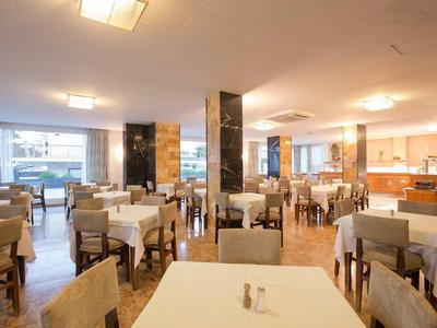 Restaurant lumineux et moderne avec de nombreuses tables et chaises aux couleurs neutres.