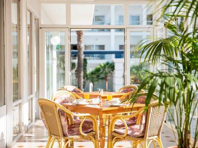 Heldere ontbijtruimte met rotanmeubels en uitzicht op buitenruimte.