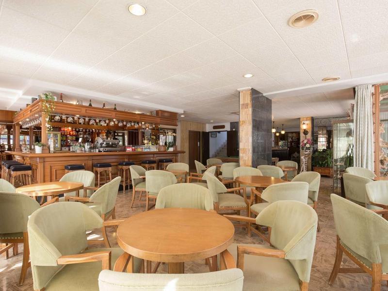 Bar d'hôtel confortable avec fauteuils moelleux et tables en bois sous un éclairage chaleureux.