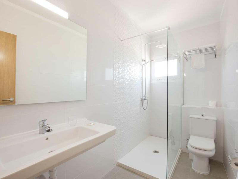 Salle de bain lumineuse avec grand lavabo, douche avec cabine en verre et toilettes.