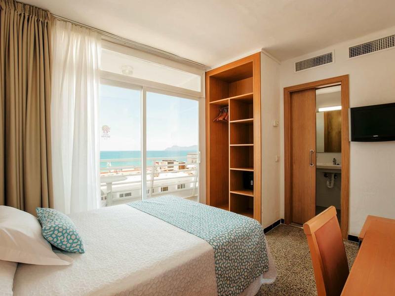 Chambre d'hôtel moderne avec lit double, grande fenêtre avec vue sur la mer et bureau.