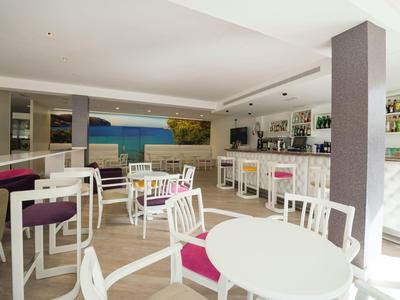 Bright breakfast room with white tables, purple chairs, and a counter with bar stools.