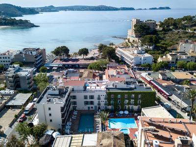 Aerial view of a coastal town with several hotels and swimming pools near the sea.