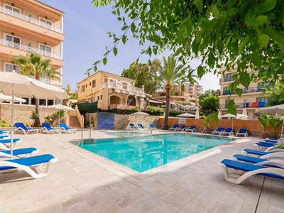 Piscina del hotel con tumbonas azules, sombrillas y edificios alrededor bajo un cielo despejado.