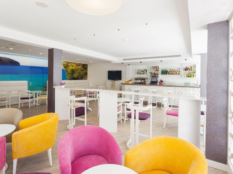 Bright, modern bar area with colorful armchairs and sea view.