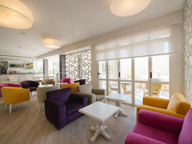 Modern bright lounge with colorful armchairs and large windows in a hotel.