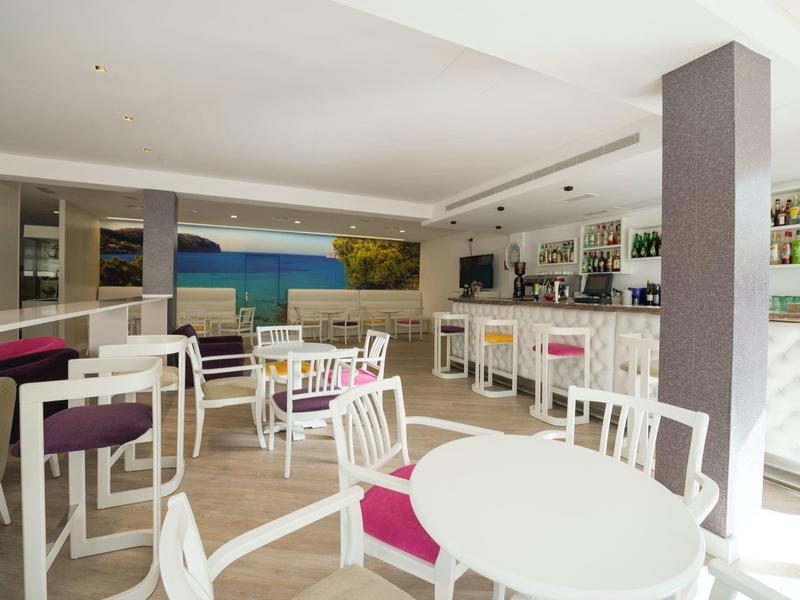 Bright breakfast room with white tables, purple chairs, and a counter with bar stools.