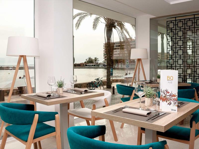 Ristorante moderno e luminoso con vista sul mare e sedie blu eleganti.