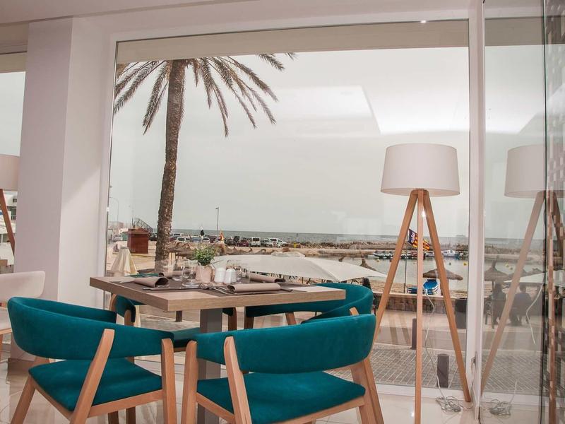 Zona pranzo moderna con sedie blu e vista mare dietro parete di vetro.