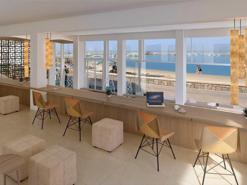 Caffè moderno con grandi finestre che si affacciano sulla spiaggia e sul mare.