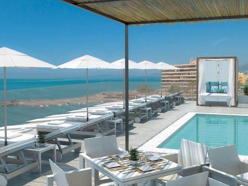 Area piscina moderna con lettini e ombrelloni con vista sul mare.