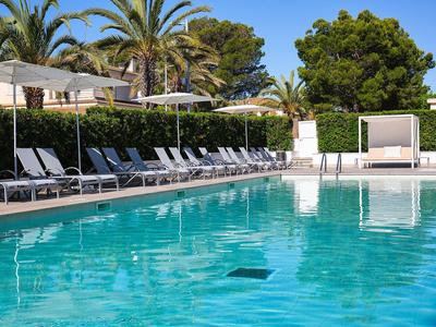 Piscine bleue claire avec chaises longues et parasols dans un cadre hôtelier tropical.