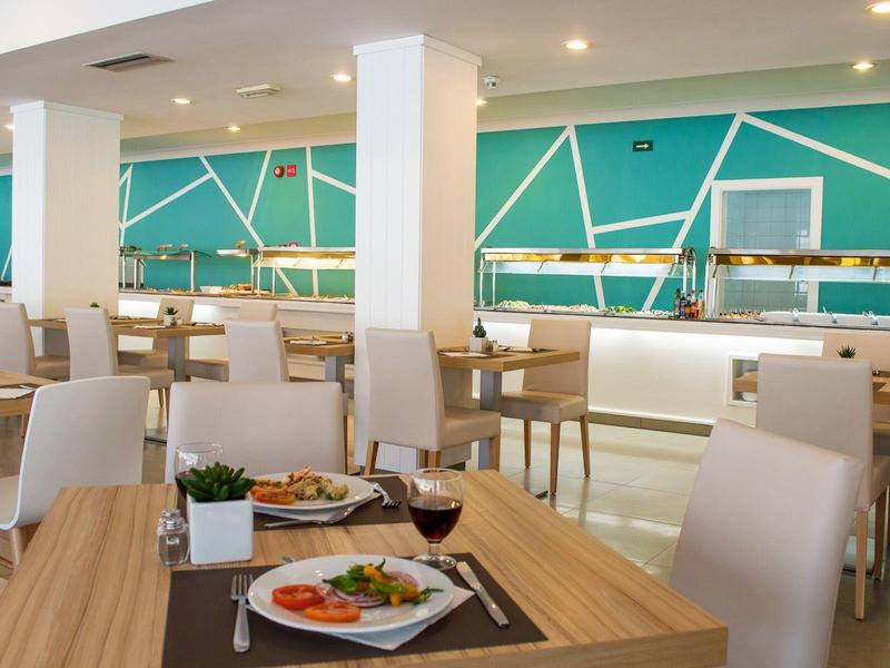 Modernes, helles Café mit weißen Stühlen, Holztischen und Wandgestaltung in Türkis und Weiß.