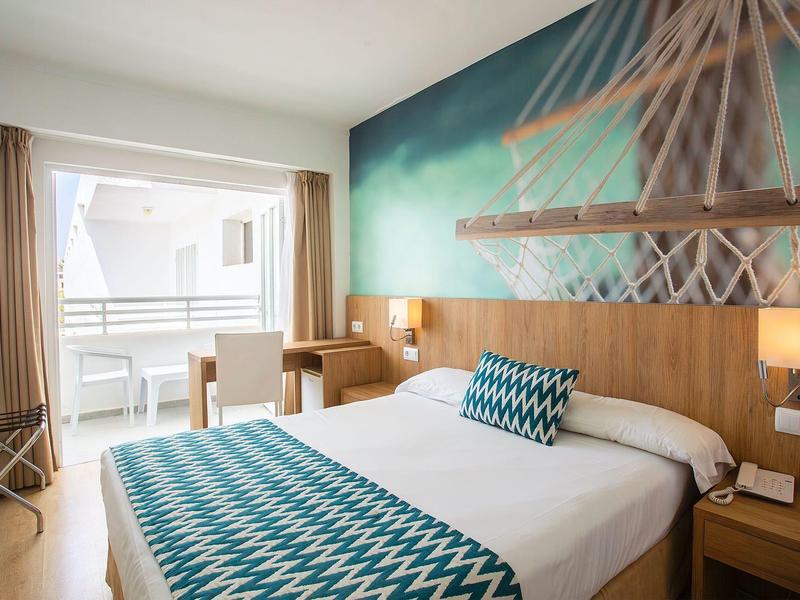 Modernes Hotelzimmer mit Doppelbett, Holzmöbeln und Balkon mit Blick nach draußen.