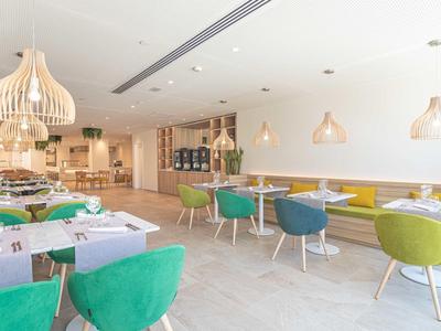 Nowoczesna, jasna restauracja z kolorowymi krzesłami i dużymi drewnianymi lampami