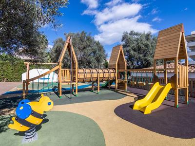 Kolorowy plac zabaw dla dzieci z zjeżdżalnią, drabinką i sprężynową pszczółką pod niebieskim niebem.