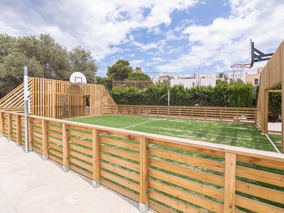 Nowoczesny teren zewnętrzny z koszem do koszykówki i drewnianym ogrodzeniem pod niebieskim niebem.