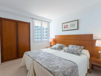 Helles Hotelzimmer mit großem Bett, Holzmöbeln und Fenster mit Blick auf Gebäude.