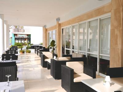 Area esterna moderna di un ristorante con tavoli e sedie in un ambiente luminoso.