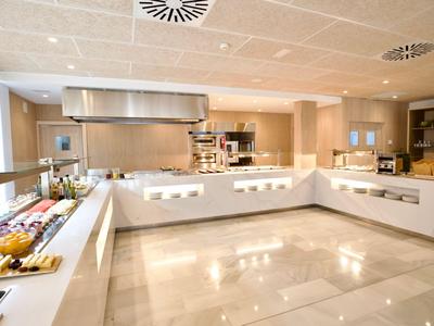 Cucina dell'hotel luminosa con attrezzature in acciaio inox e banconi intorno.