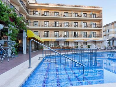 Modern buitenzwembad met trap en uitzicht op een meerlagig hotelgebouw.